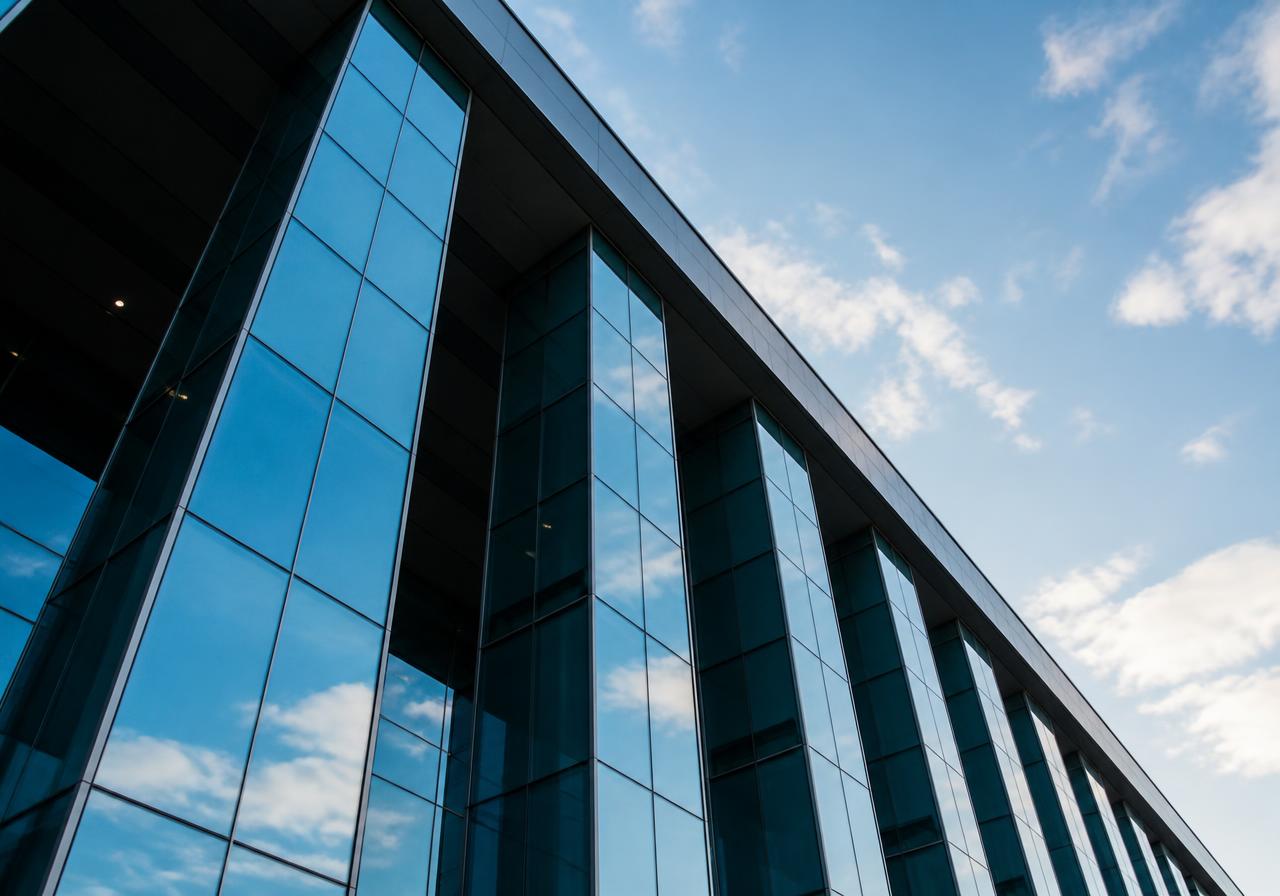 Modern glass office building rising against a blue sky